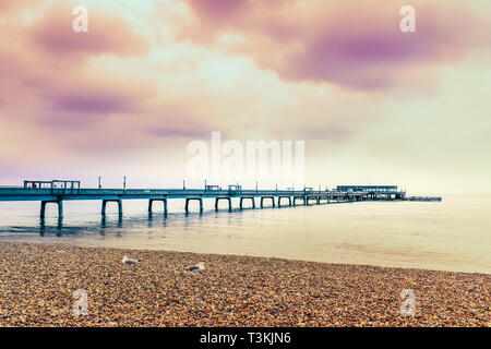 Dramatischer Abendhimmel über Deal Pier in Kent, Großbritannien. Zwei Möwen sitzen auf dem Kiesstrand im Vordergrund. Stockfoto