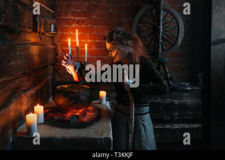 Beängstigend Hexe liest Bann über den Topf, Seance Stockfoto