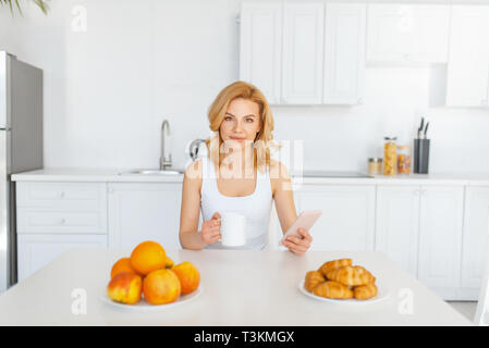 Glückliche Frau an der Tabelle mit Früchten und Backen Stockfoto