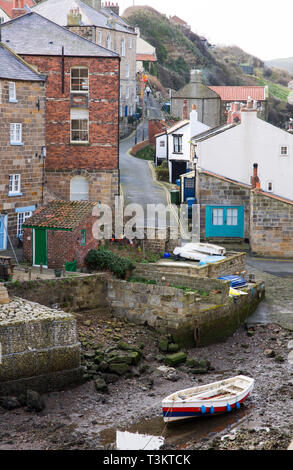 Klinker gebaut Boot bei Ebbe und Häuser in Staithes, ein traditionelles Fischerdorf und Badeort an der Küste von North Yorkshire, England, UK. Stockfoto