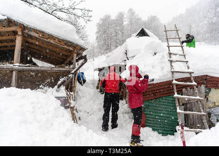 Wanderer freiwillig helfen den Schnee in einem abgelegenen Kloster auf dem Hauptweg auf 1400 m Höhe im Nationalpark Retezat, Rumänien entfernt Schaufeln, Stockfoto