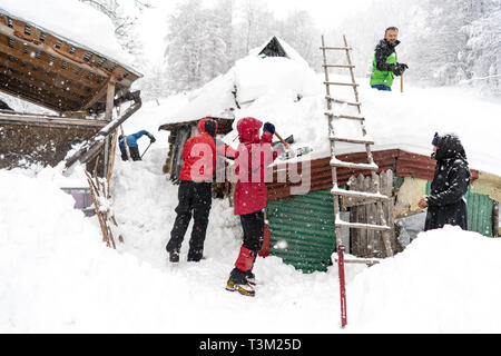 Wanderer freiwillig helfen den Schnee in einem abgelegenen Kloster auf dem Hauptweg auf 1400 m Höhe im Nationalpark Retezat, Rumänien entfernt Schaufeln, Stockfoto