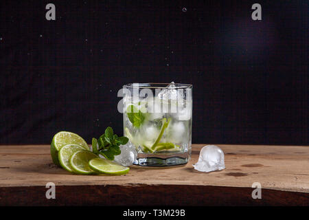 Mojito Sommer Strand erfrischenden tropischen Cocktail in Glas mit Spritzern und Tropfen: Sodawasser, Limettensaft, Minze, Zucker, Eis und Rum auf Vintage werde Stockfoto