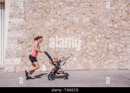 Junge Mutter mit dem Kinderwagen für Ihr Baby nach der Geburt in Form zu bleiben. Stockfoto