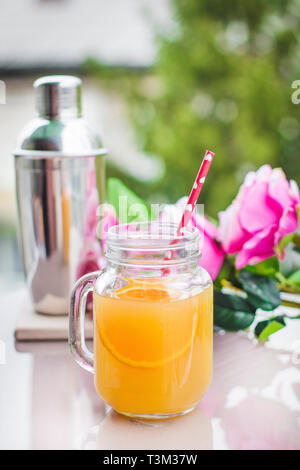 Orangensaft Cocktail in einem Glas mit Rosen und einen Shaker