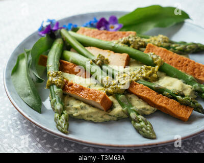 Wilder Knoblauch Hummus mit Spargel, Smokey Tofu und Koriander Pesto Stockfoto