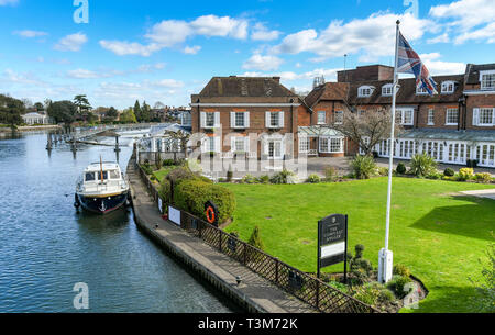 MARLOW, ENGLAND - MÄRZ 2019: Zeichen und flag Pole außerhalb des Compleat Angler Hotel auf der Themse in Marlow mit einem Motorboot neben vertäut. Stockfoto