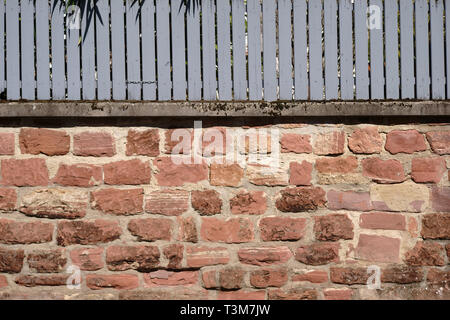 Eine rustikale Mauer versetzt und gebrochene Backsteine mit einem Holzzaun. Stockfoto