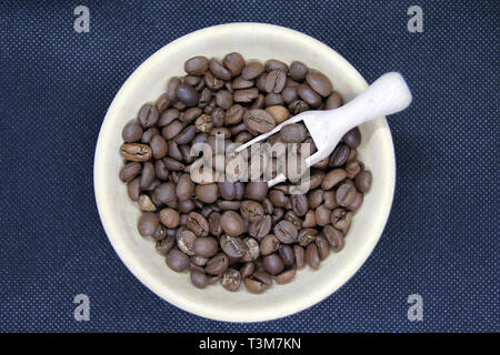 Kleine Schale aus Holz voll von gerösteten Kaffeebohnen. Geröstete Kaffeebohnen. Stockfoto