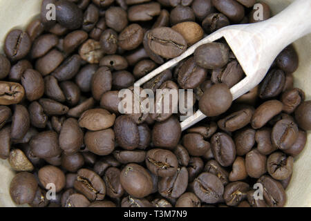 Kleine Schale aus Holz voll von gerösteten Kaffeebohnen. Geröstete Kaffeebohnen. Stockfoto