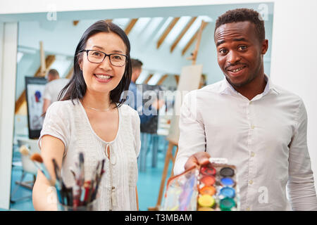 Multikulturelle Künstlerpaar mit Pinsel und inkbox in einem Malworkshop Stockfoto