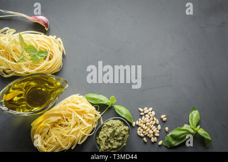 Grenze der rohen Nudeln Hartweizen, Pesto, frischem Basilikum, Parmesan zum Kochen mediterrane Gerichte. Ansicht von oben, Platz für Text. Stockfoto