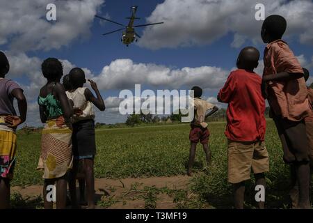 Kinder in Mosambik ein US Air Force Hubschrauber nehmen Sie nach der Lieferung der Nahrungsmittelhilfe im Gefolge der massiven Cyclone Idai April 8, 2019 in Bebedo, Mosambik. Das World Food Programm, mit Hilfe von der US Air Force ist Transport der Hilfsgüter der verwüsteten Region zu unterstützen. Stockfoto