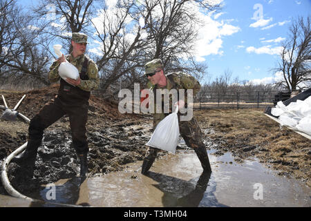 North Dakota Armee Nationalgarde stand in Hochwasser, wie sie Sandsäcke steigende floodwater von der Sicherung durch ein Abfluss Kanal in einem Bauernhof im ländlichen Cass County April 8, 2019 in der Nähe von West Grand Forks, North Dakota zu Block platzieren. Der Datensatz Hochwasser soll als späten winter storm Fässer in den Mittleren Westen der USA in den nächsten Tagen verschlechtern. Stockfoto