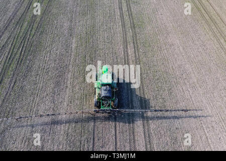 Traktor mit aufklappbaren Sprühen von Pestiziden. Düngung mit einem Traktor, in Form eines Aerosols auf dem Gebiet der Winterweizen Stockfoto