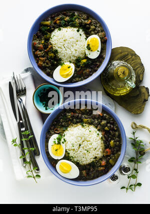 Reis mit schwarzen Bohnen und gekochtes Ei auf den Tisch mit Gewürzen und Olivenöl. Gesunde karibisches Essen Stockfoto