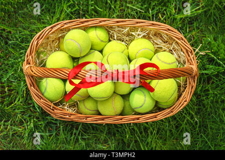 Tennis Ostern mit Tennis Bälle in einen Korb auf grünem Gras. Selektiver Fokus, Kopieren, Ansicht von oben, flach. Stockfoto