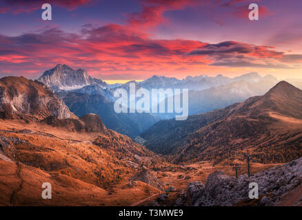 Bunte Roter Himmel mit Wolken über die Berge im Nebel bei Sonnenuntergang im Herbst. Dolomiten, Italien. Landschaft mit Bergen, Hügeln mit Oran Stockfoto