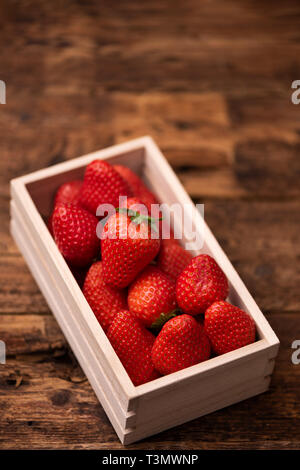 Frische Erdbeeren im Korb auf hölzernen Tisch Stockfoto