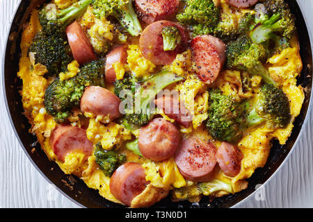 Leckere heiße Omelette mit Brokkoli und Würste in einer Pfanne bestreut mit frisch gemahlenem Pfeffer, horizontale Ansicht von oben, flach, Clos Stockfoto