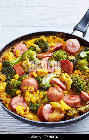 Leckere heiße Omelette mit Brokkoli und Würste in einer Pfanne mit frisch gemahlenem Pfeffer, vertikale Ansicht von oben gesprengt ist, Stockfoto