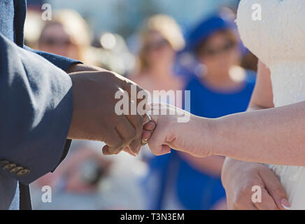 Pflegen Sie einen Ring am Finger auf Bräute Hochzeit mit gemischten Rennen Paar Stockfoto