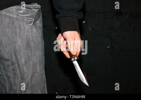 Ein junger Mann mit einem balisong oder Butterfly Messer für Schutz auf einer Straße in Newport, South Wales. 09/07/2006 Stockfoto