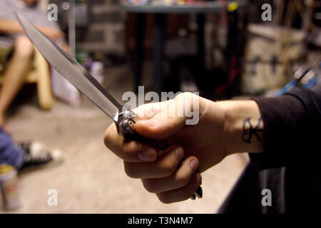 Ein junger Mann mit einem balisong oder Butterfly Messer für Schutz auf einer Straße in Newport, South Wales. 09/07/2006 Stockfoto