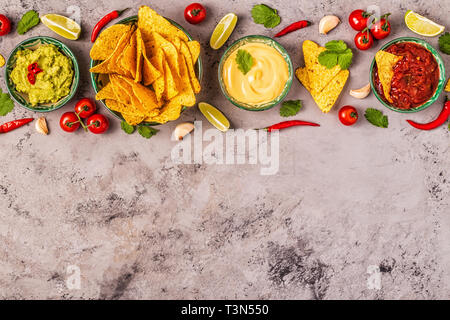 Mexikanisches Essen Hintergrund: Guacamole, Salsa, cheesy Soßen mit Nachos, Ansicht von oben. Stockfoto