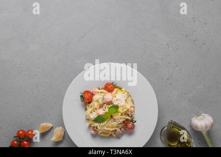 Pasta Tagliatelle mit Forellen und Sahne, Käse, Tomate, Knoblauch auf hellen Hintergrund. Köstliche mediterrane Mittagessen. Ansicht von oben. Stockfoto