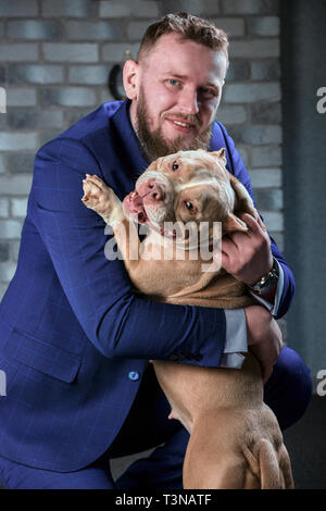 Hund Bulli und ihre Besitzer, ihre liebevolle Meister, der den Hund in ihren Armen, Umarmungen und Küsse hält. Der Hund fühlt sich gut auf die Hand des Besitzers Stockfoto