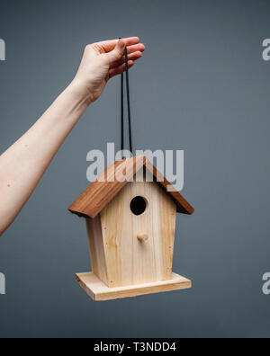 Erwachsene Frau Hand, die von einem Thread Vögel nisten Vogelhaus Haus im Garten an einem Baum erhängt installiert werden Stockfoto