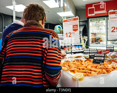 Paris, Frankreich - 29 Mar 2019: Rückansicht der älteren Frau, unterstützt von Verkäufer zu kaufen frische Garnelen im Supermarkt fisch Marktstand in der modernen französischen Store Stockfoto