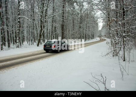 Auto fahren auf asphaltierten Straße durch den Wald im Schnee bedeckt - fuzzy Blick auf die Auto Stockfoto