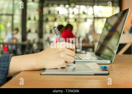 Hand mit digitalen Tablett und Stift penand Arbeiten am Laptop. Stockfoto