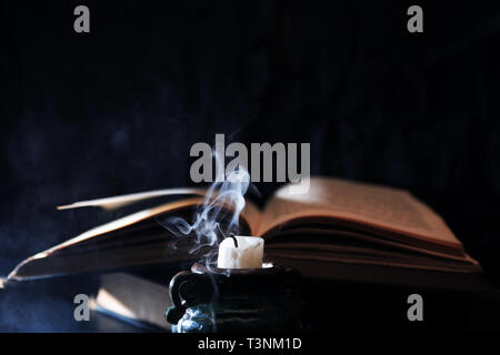 Stillleben mit Kerze erloschen und blauer Rauch in der Nähe von Altes Buch Stockfoto