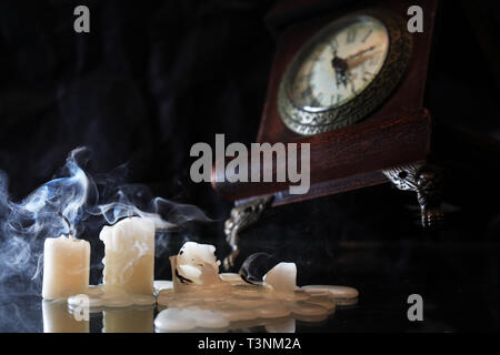 Einstellen der ausgelöschten Kerzen in der Nähe von Alte Uhr an schönen dunklen Hintergrund Stockfoto