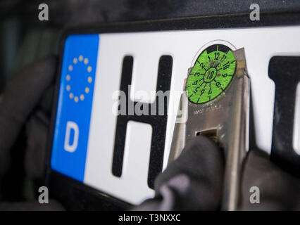 Hannover, Deutschland. 10 Apr, 2019. Ein Mitarbeiter von TÜV Nord entfernt eine TÜV-Plakette als Teil einer HU Hauptuntersuchung. Credit: Julian Stratenschulte/dpa/Alamy leben Nachrichten Stockfoto