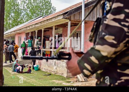 Shadipora, Jammu und Kaschmir, Indien. 11. April, 2019. Indien - eine paramilitärische Trooper gesehen stehen auf der Hut wie Kaschmir Wähler Warteschlange während der ersten Phase der allgemeinen Wahlen im Shadipora. Die erste Phase der allgemeinen Wahlen begann mit Wahlen in 91 Wahlkreisen in 18 Mitgliedstaaten verteilt und zwei Union Territories. Die Jammu und Kaschmir erfasst 47% Prozent Wahlbeteiligung. Credit: Saqib Majeed/SOPA Images/ZUMA Draht/Alamy leben Nachrichten Stockfoto