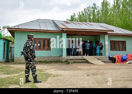 Shadipora, Jammu und Kaschmir, Indien. 11. April, 2019. Indien - eine paramilitärische Trooper gesehen stehen auf der Hut wie Kaschmir Wähler Warteschlange während der ersten Phase der allgemeinen Wahlen im Shadipora. Die erste Phase der allgemeinen Wahlen begann mit Wahlen in 91 Wahlkreisen in 18 Mitgliedstaaten verteilt und zwei Union Territories. Die Jammu und Kaschmir erfasst 47% Prozent Wahlbeteiligung. Credit: Saqib Majeed/SOPA Images/ZUMA Draht/Alamy leben Nachrichten Stockfoto