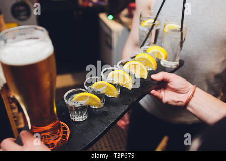 Männliche Hände jubeln mit Brille der Schuß oder Likör. Freunde trinken erschossen oder Likör und Prost. Männliche Hände jubeln mit Alkohol auf unscharfen bar Hintergrund. P Stockfoto