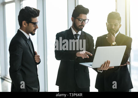 Die Silhouetten der drei asiatischen Führungskräfte stehen vor Windows Diskussion von mit Laptop Computer. Stockfoto