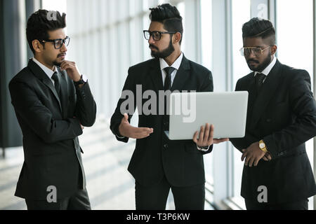 Die Silhouetten der drei asiatischen Führungskräfte stehen vor Windows Diskussion von mit Laptop Computer. Stockfoto