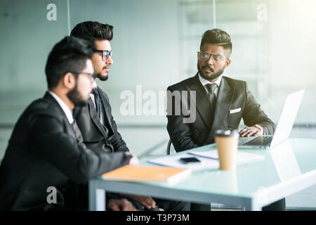 Drei Geschäftsleute sitzen um den Tisch treffen In modernen Großraumbüro Stockfoto