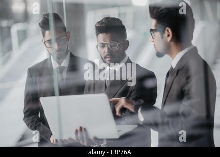 Die Silhouetten der drei asiatischen Führungskräfte stehen vor Windows Diskussion von mit Laptop Computer. Stockfoto