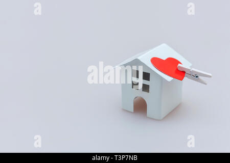 Einfach minimalistisches Design mit kleinen weißen Spielzeug Haus und rotes Herz auf weißem Hintergrund. Hypothek Sachversicherung Dream Home Konzept. Kopieren Stockfoto