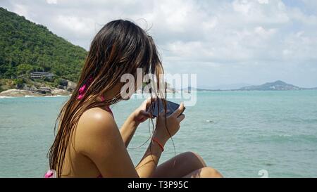 Junge aisan Frau spielen mit mobilen phoe am Meer Stockfoto