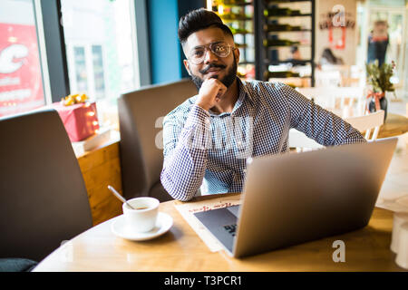 Junge asiatischer Mann mit Laptop im Cafe hat. Ein Mann mit Laptop Stockfoto