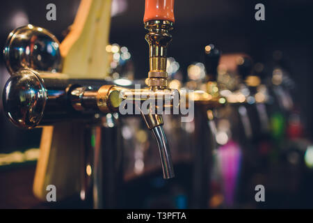 Die Theke mit Flaschen und Vorrichtung zum Dosieren von Bier. Vorrichtung zum Dosieren von Bier an der Bar. Pub. Die Bar im Restaurant. Geräte Stockfoto