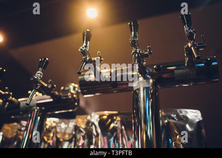 Die Theke mit Flaschen und Vorrichtung zum Dosieren von Bier. Vorrichtung zum Dosieren von Bier an der Bar. Pub. Die Bar im Restaurant. Geräte Stockfoto